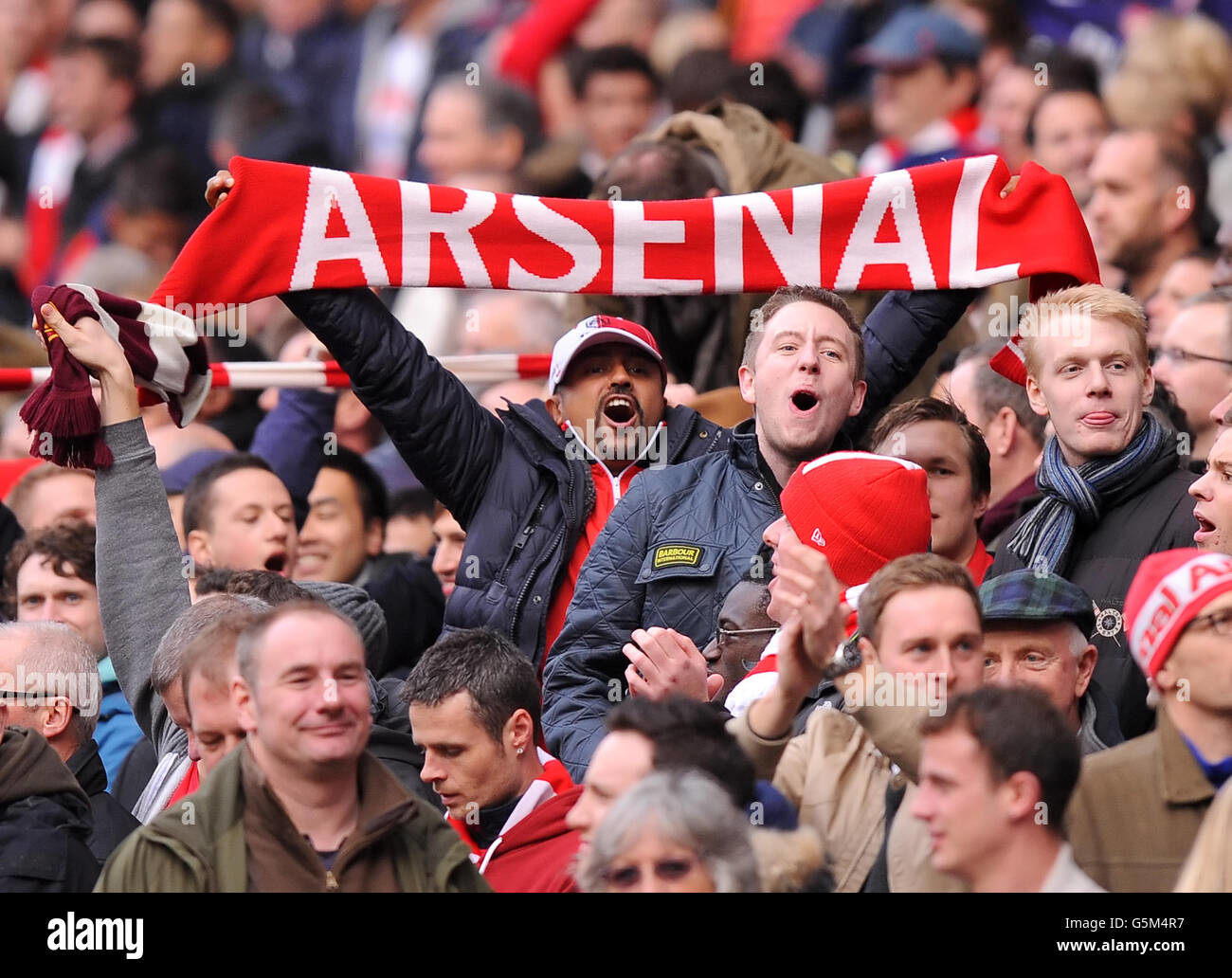 Arsenal supporters show enthusiastic support in stadium stands during a football match