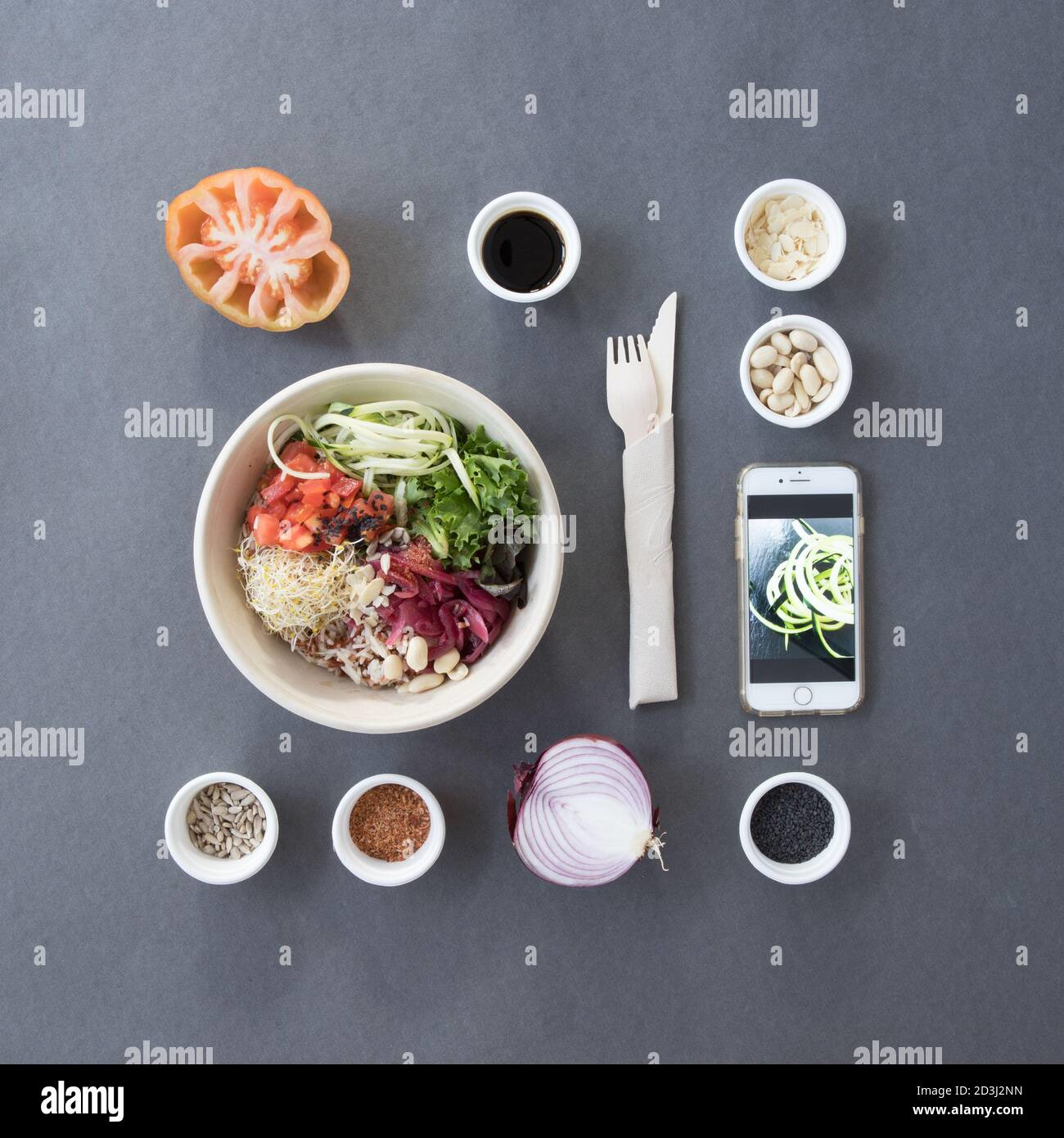 Overhead flat lay of a vibrant salad bowl surrounded by fresh ingredients and minimalistic tools for food photography composition.
