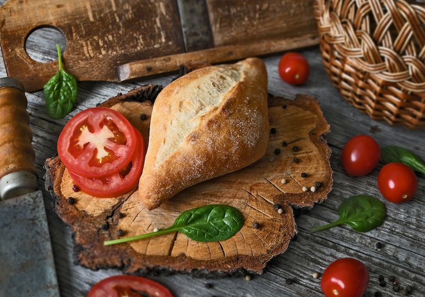 Rustic food styling with bread, tomatoes, spinach, and wooden props showcasing natural textures and balanced composition.