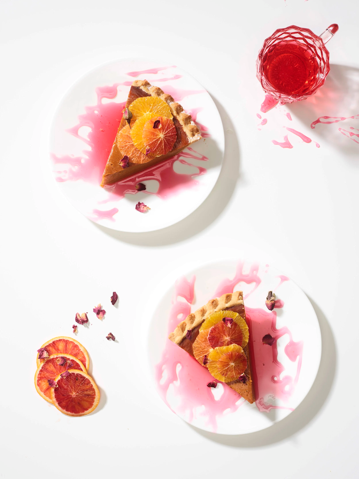 Two slices of citrus-topped pie with a pink sauce and complementary elements showcasing color contrast in food photography composition.