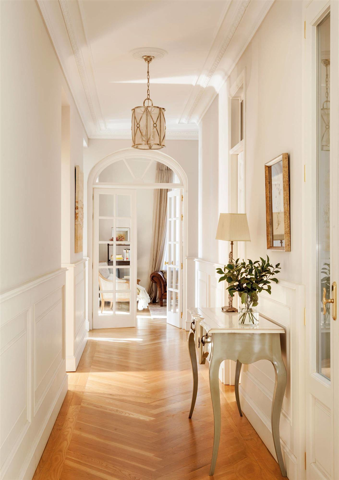 A bright and elegant home entrance with a hanging lamp, console table, and natural light enhances the welcoming atmosphere
