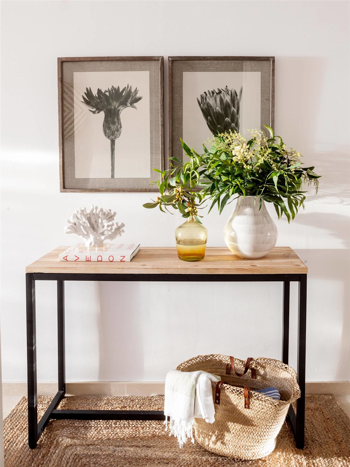 Home entrance decorated with a wooden console table, framed botanical prints, decorative vases with plants, and a woven basket for an inviting look