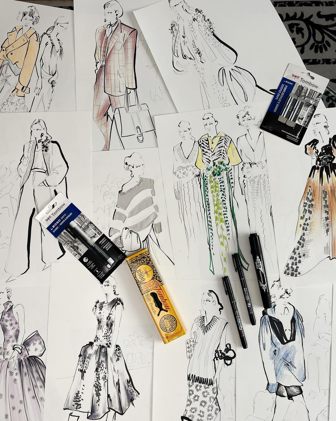 A collection of hand-drawn fashion sketches with color accents and drawing tools, showcasing the essential role of sketching in fashion design creativity
