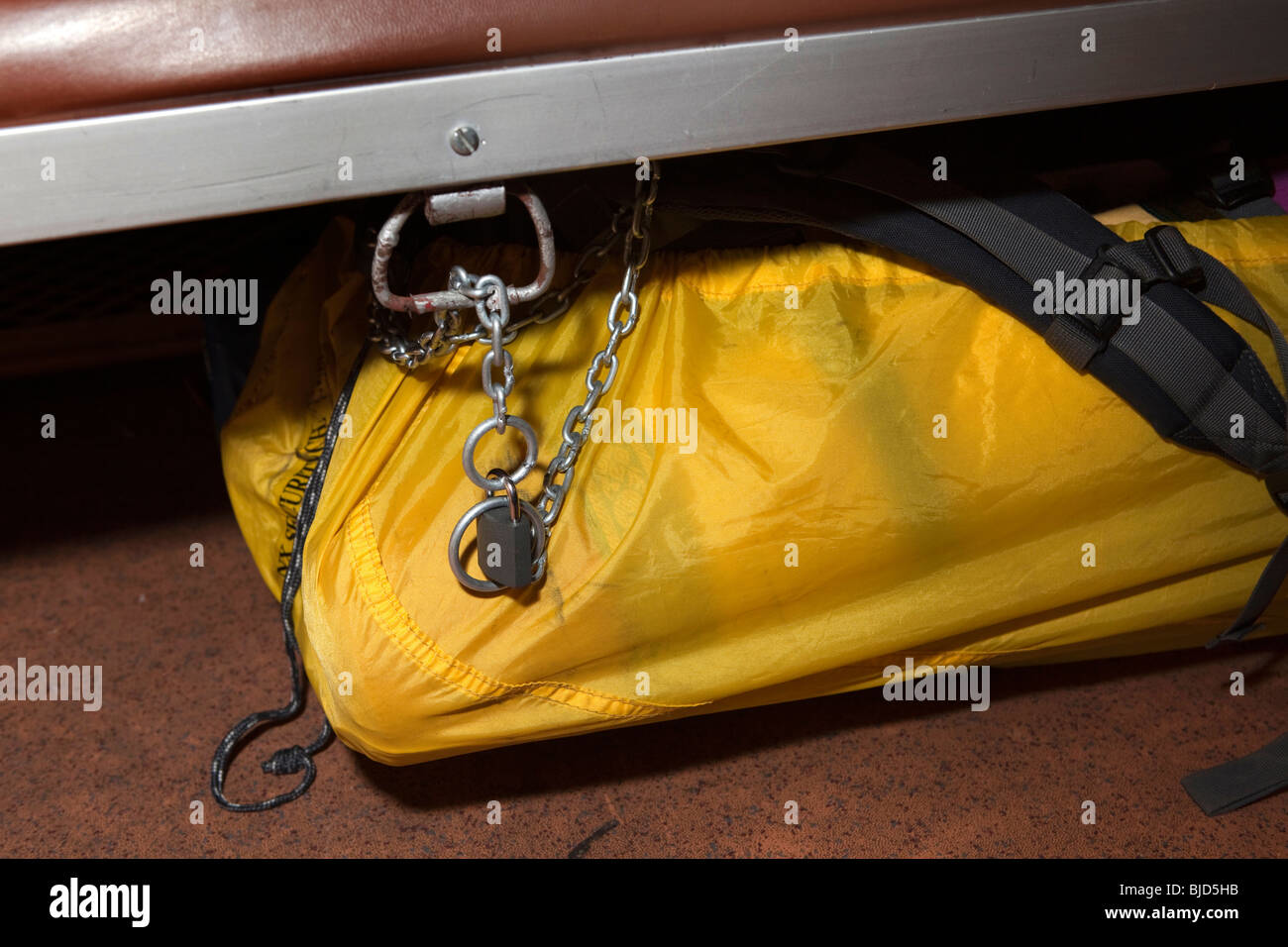 A yellow bag secured with a chain and padlock under an Indian train seat to ensure luggage safety