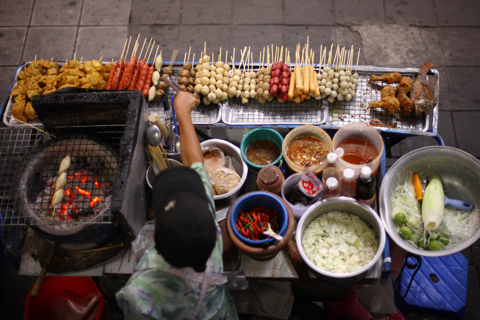 Street food vendor grilling affordable skewered snacks and local delicacies in Southeast Asia, illustrating budget-friendly meal options for travelers