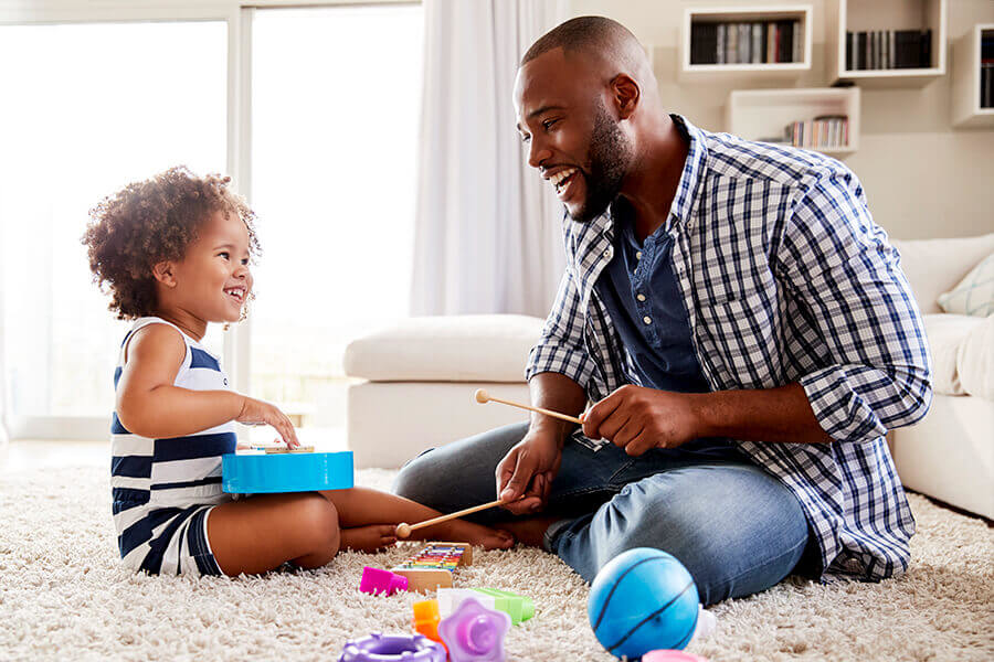 Adult and child engaged in floor play with musical toys illustrating DIR/Floortime therapy concepts.