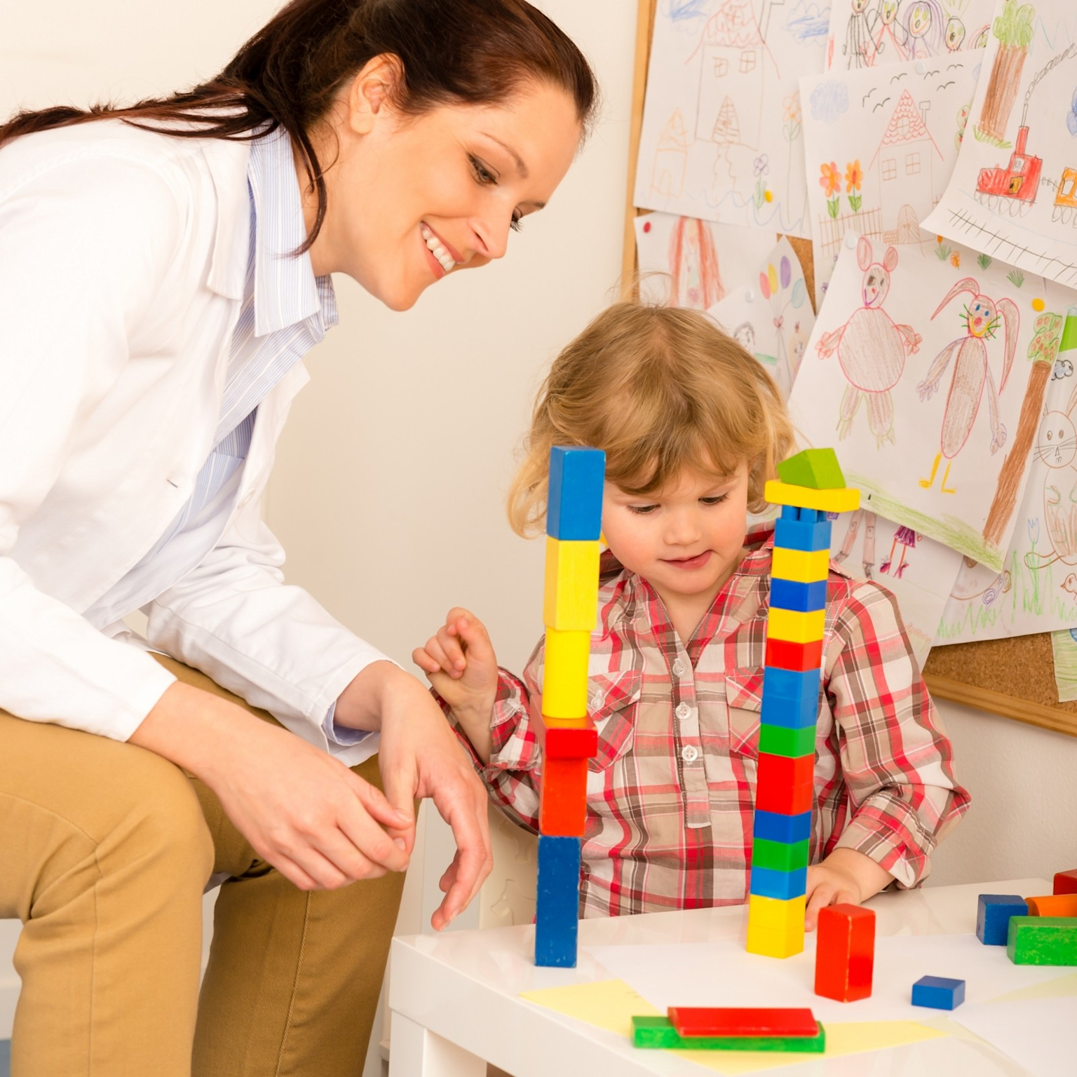 Child engaged in an ABA therapy session with a therapist using colorful blocks to support learning and development.
