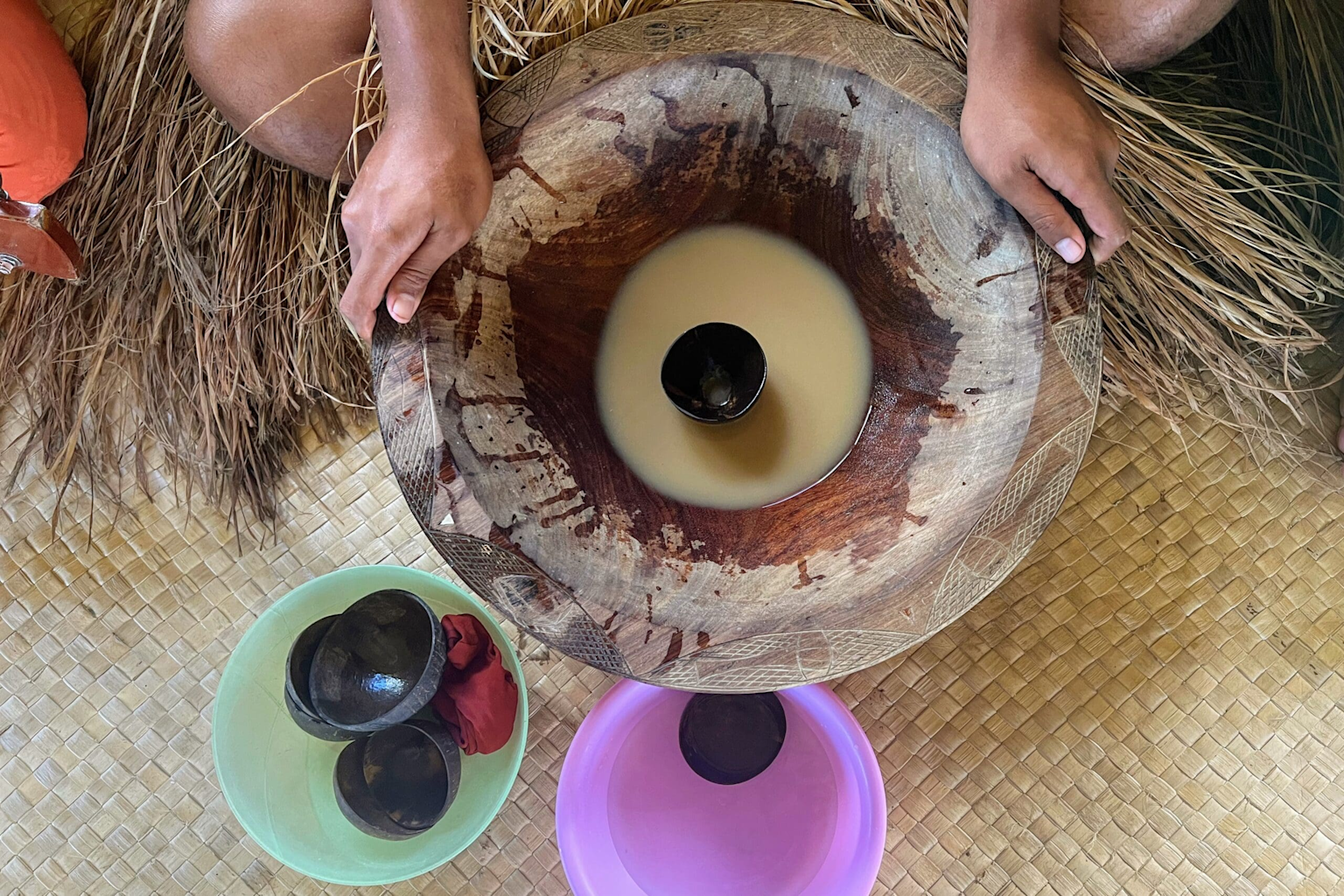 Traditional Fijian kava ceremony with carved wooden bowl and cups on woven mat