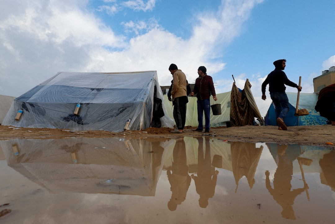 Displaced families in Gaza refugee camps struggle with flooding as tents are protected with plastic sheeting during rainy weather