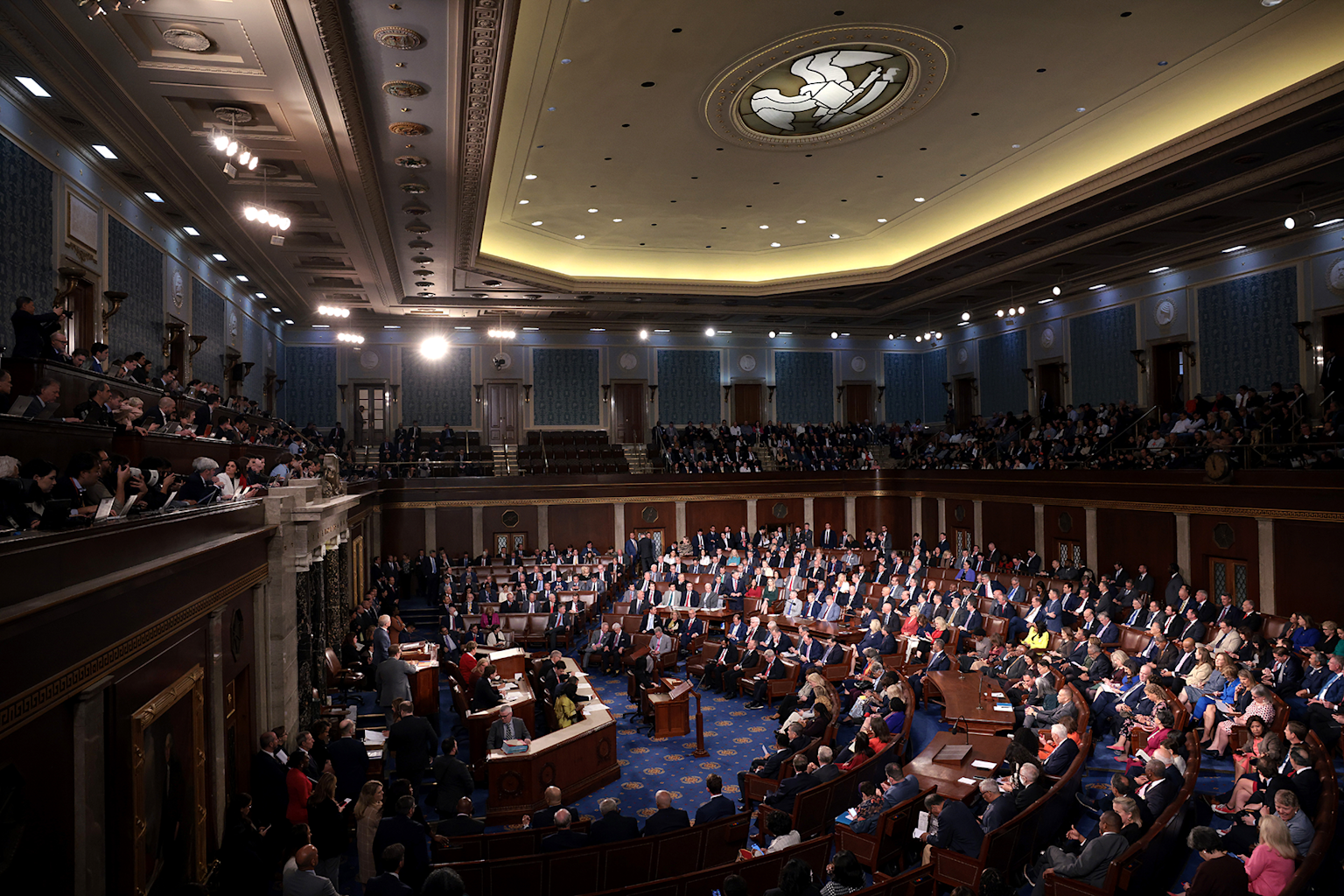 A legislative chamber filled with policymakers and officials during a formal government session, illustrating the setting for healthcare regulatory discussions