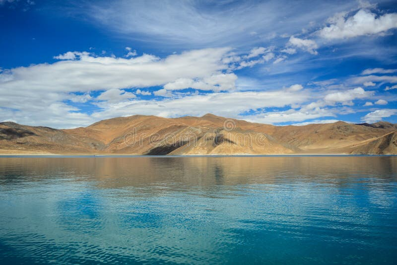 Turquoise waters of Pangong Lake reflecting the Himalayan mountains under a vibrant sky