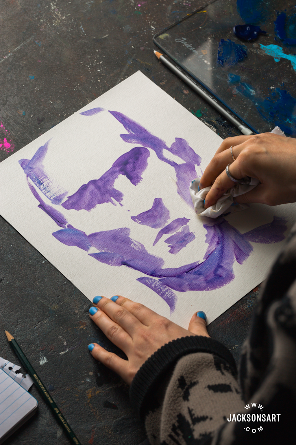 An artist working on a purple underpainting or sketch on canvas, demonstrating the foundational sketching process in painting