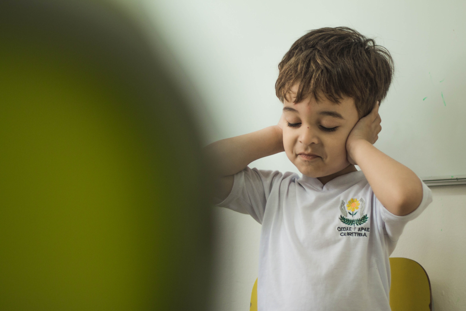Child covering ears to block out sound, illustrating sensory sensitivity often experienced in autism.