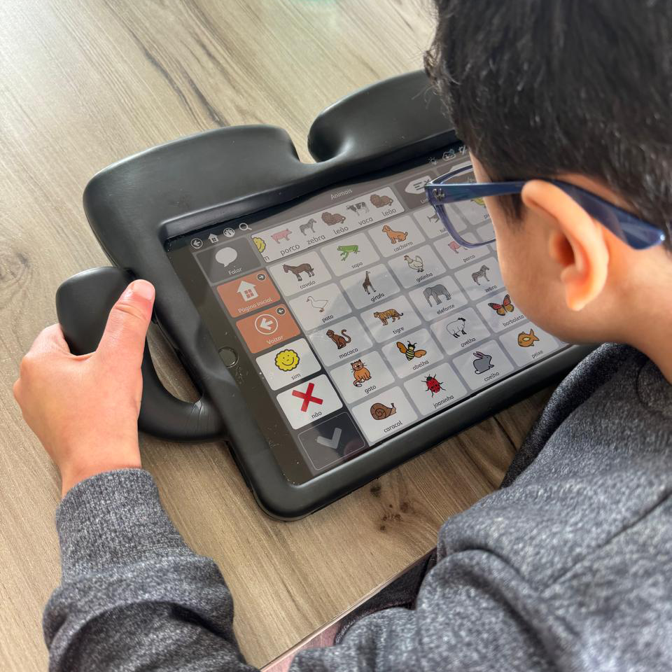 Child using an augmentative and alternative communication tablet app with animal icons to aid communication.