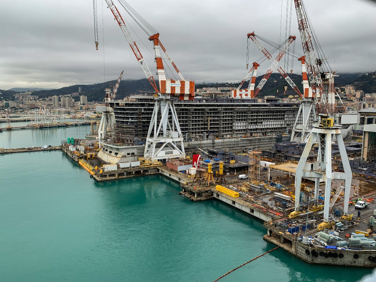 Fincantieri shipyard in Italy with large ship under construction featuring multiple cranes and industrial equipment
