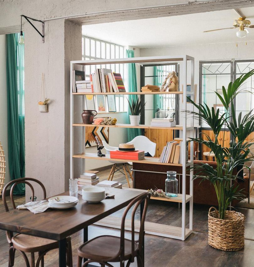 Open bookshelf used as a room divider to separate living and dining areas without construction