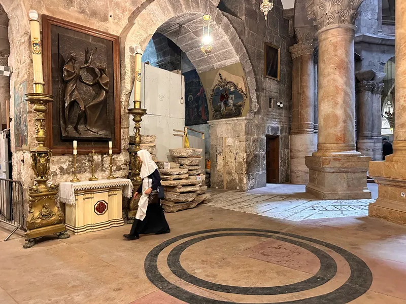 Interior view of a chapel within the Church of the Holy Sepulchre featuring a nun and religious artifacts