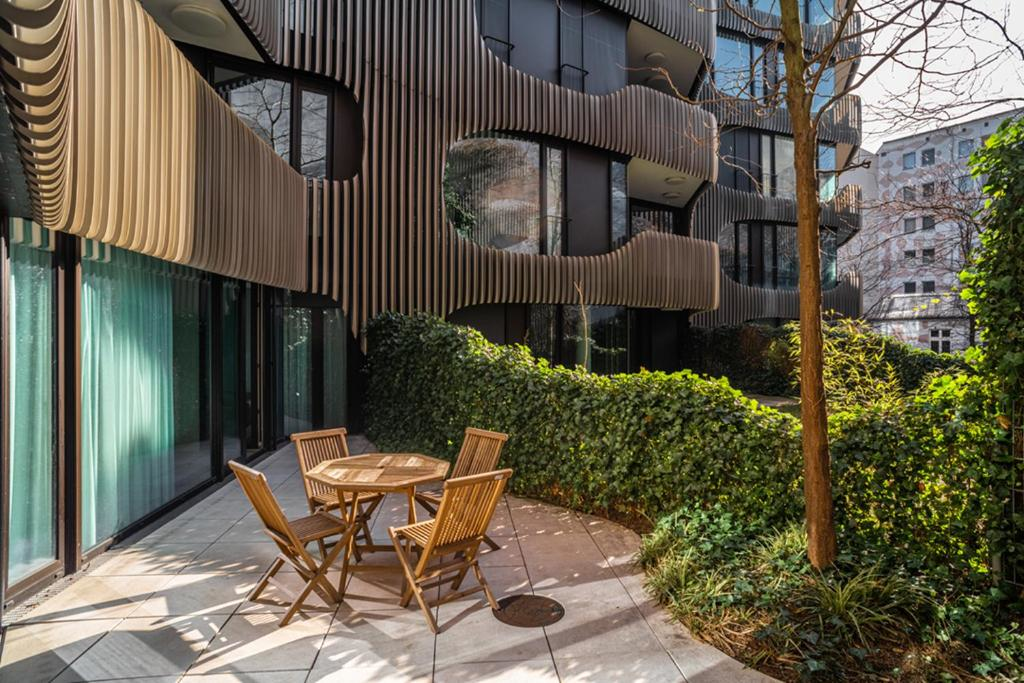 Outdoor patio area with a wooden table and chairs in a luxury Berlin Mitte apartment building surrounded by greenery