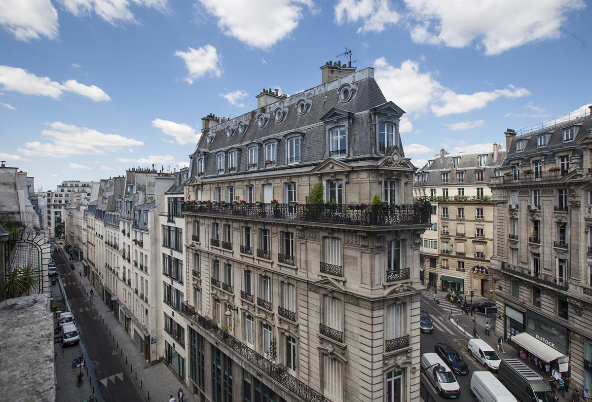Haussmannian apartment building in Paris featuring classic mansard roof and wrought iron balconies