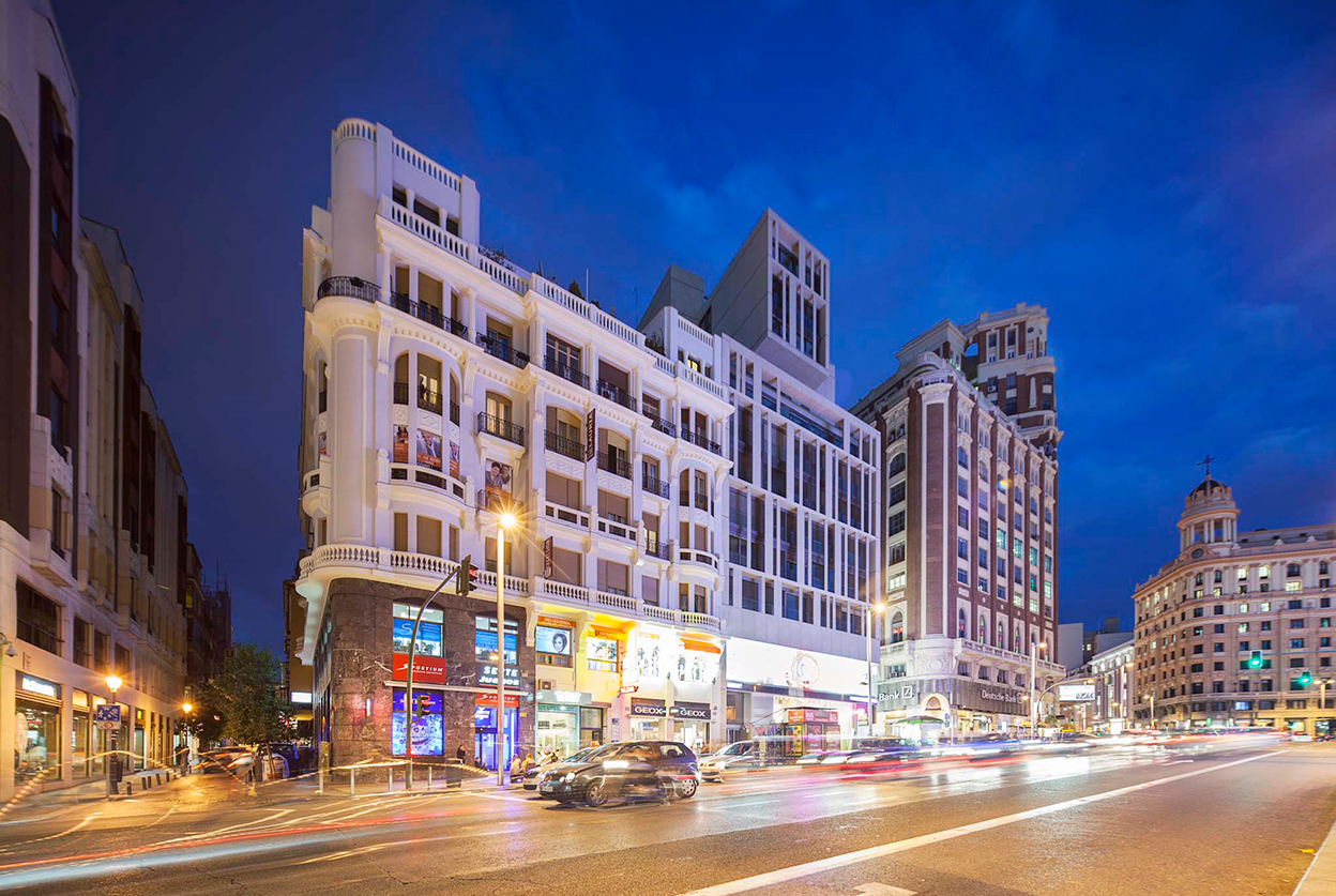 Twilight view of luxury residential and commercial buildings on Madrid's Gran Via with dynamic city traffic and illuminated architecture