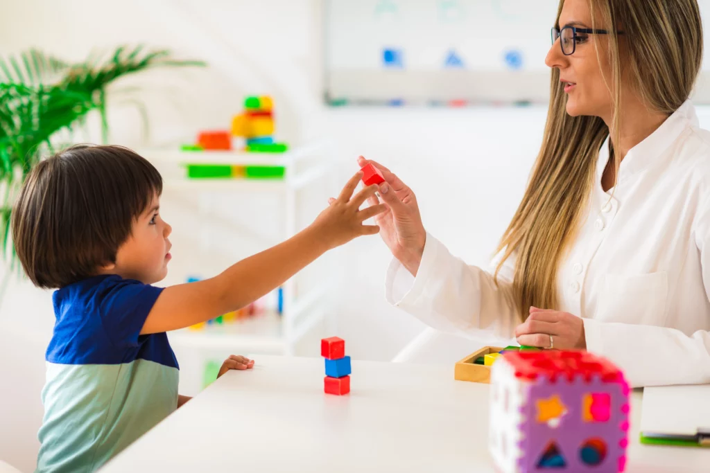 A healthcare professional engaging in occupational or speech therapy with a child, which is relevant in autism therapy contexts.