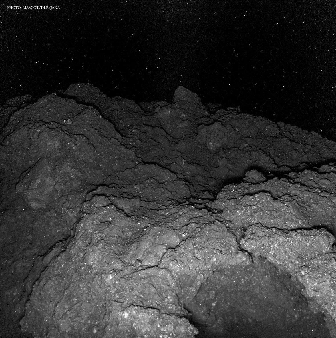 Close-up view of an asteroid's rocky surface with boulders against the starry backdrop of space
