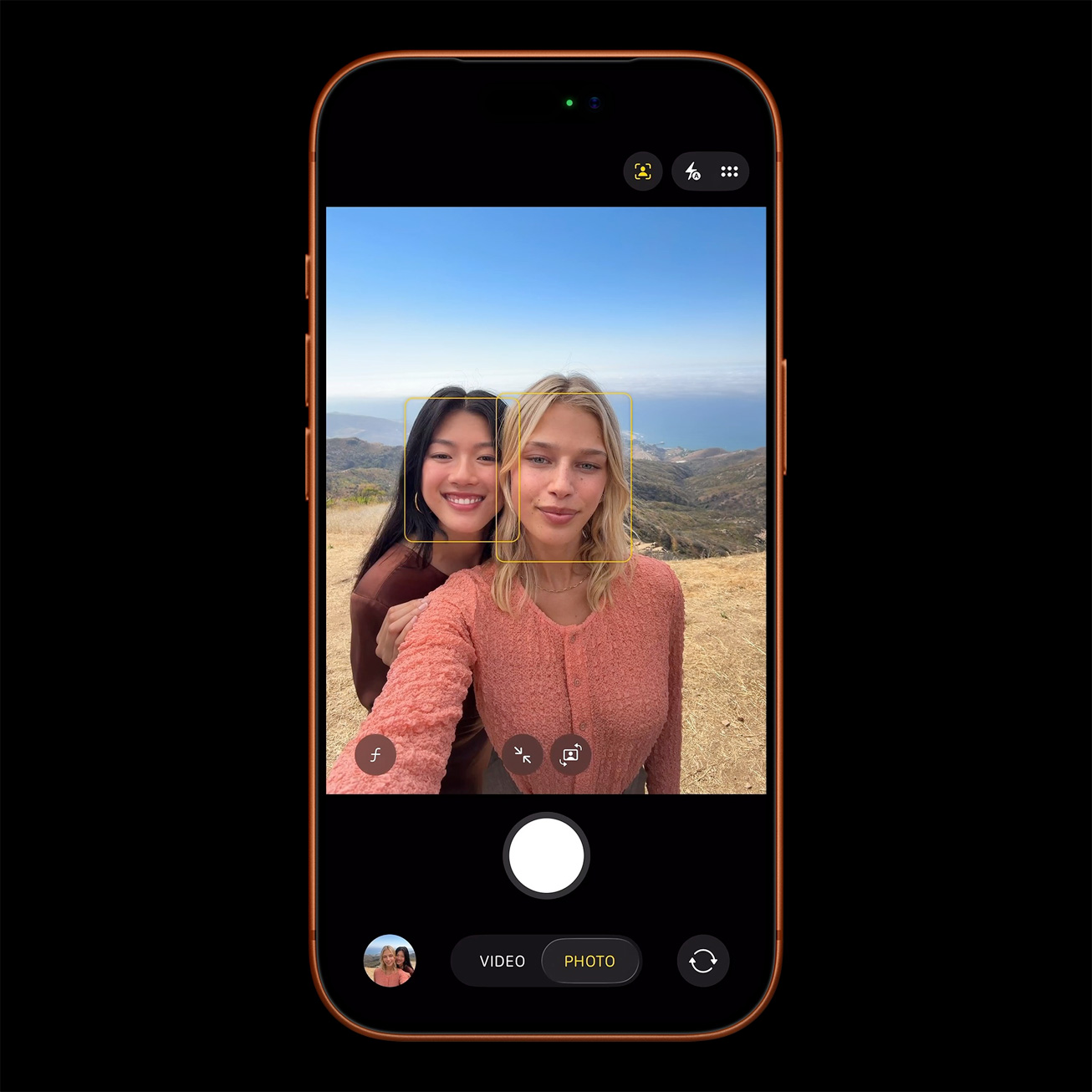 iPhone camera app interface showing selfie mode with focus on two faces against a scenic outdoor background, illustrating advanced camera features