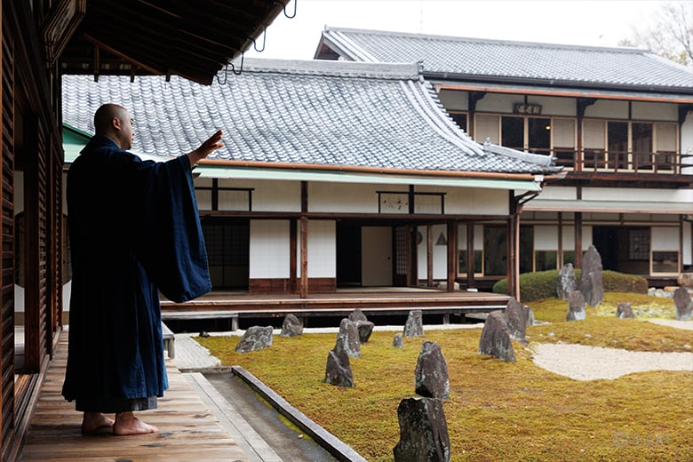 A traditional Japanese monk practicing meditation in a tranquil Zen rock garden at a historic temple