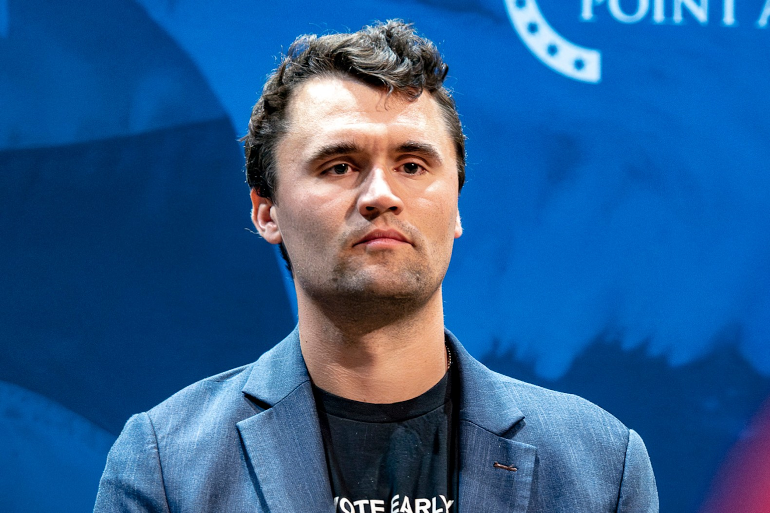 Charlie Kirk, founder of Turning Point USA, pictured at a Turning Point USA event with the organization's logo in the background