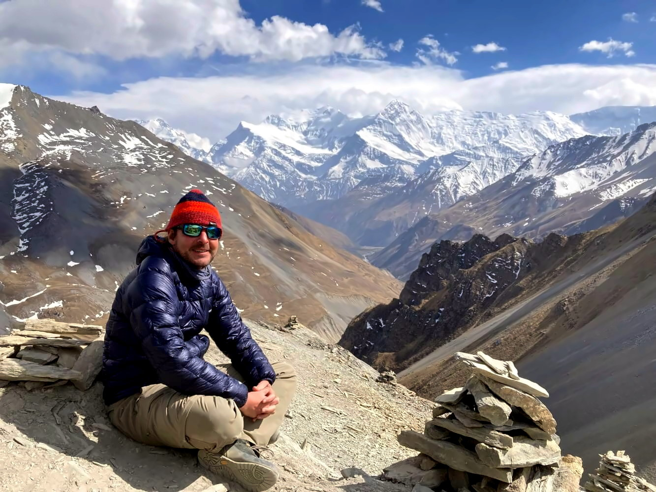 A trekker resting on the Annapurna Circuit trail with the breathtaking snow-capped Himalayas in the backdrop, symbolizing adventure and cultural immersion