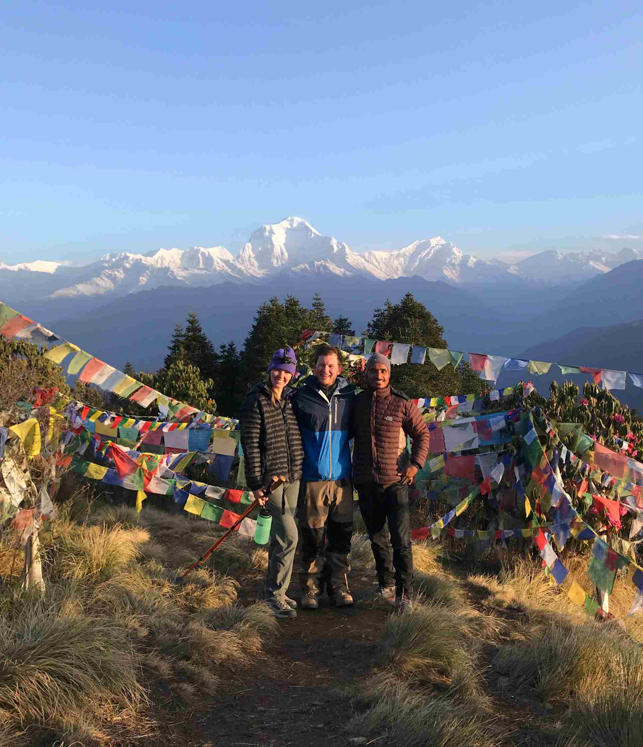 Hikers on the Annapurna Circuit trek in Nepal surrounded by Himalayan peaks and colorful prayer flags
