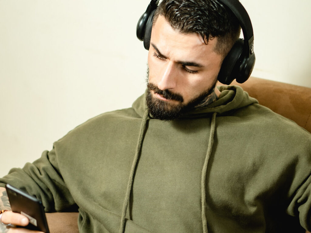 A person listens to audio with headphones while holding a smartphone, illustrating the shadowing technique for language learning.