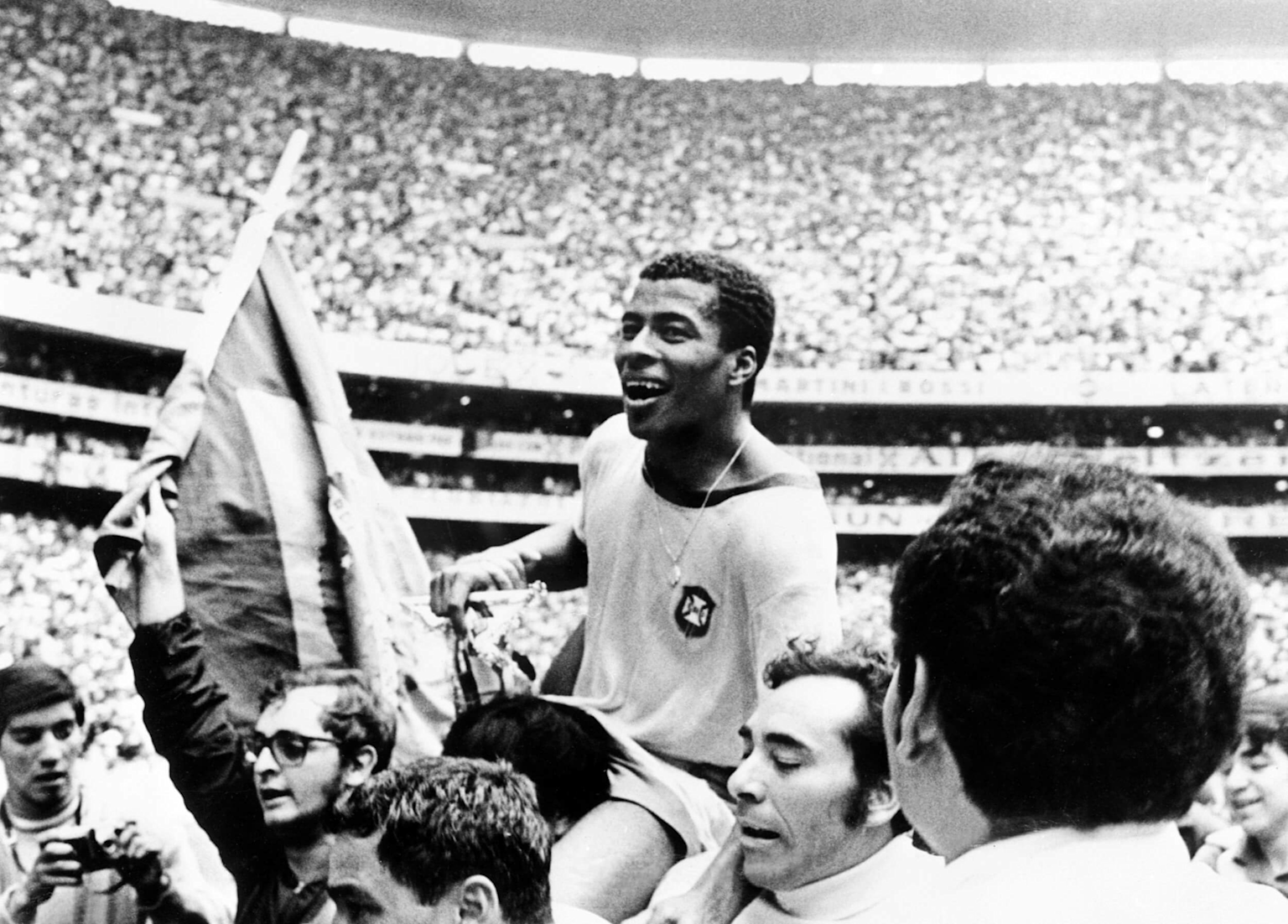 Brazilian football player celebrates winning the 1970 World Cup, carried by teammates in a packed stadium