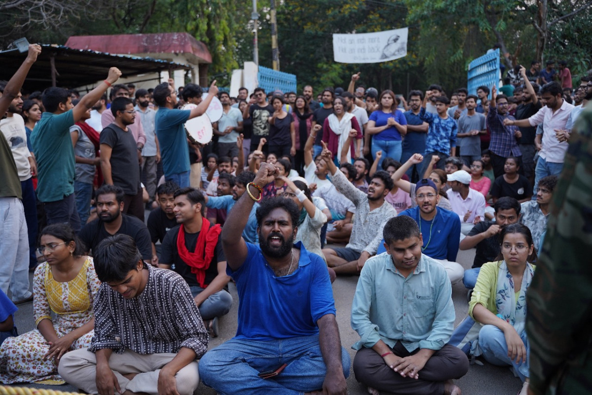 College students sitting and raising fists in protest during a strike over fee reimbursement issues in Telangana