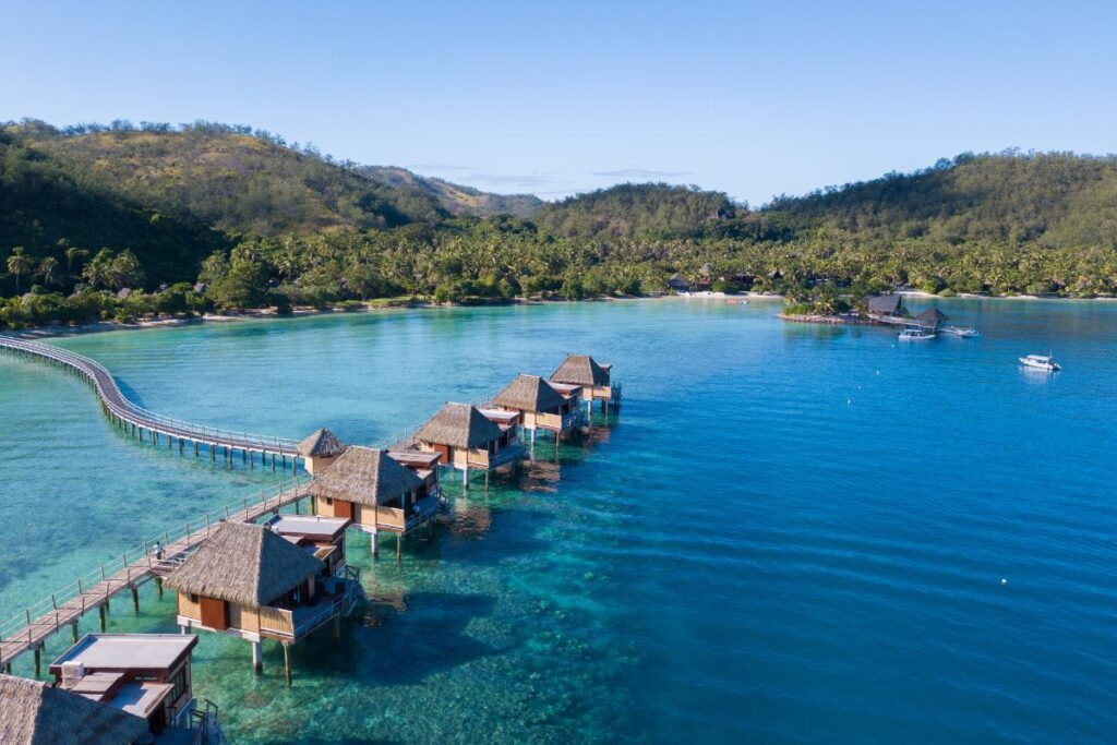 Luxury overwater bungalows in Fiji set above crystal-clear turquoise waters with a lush tropical island backdrop