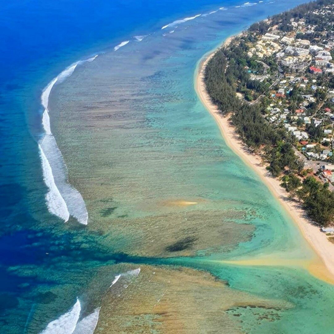 Aerial view of Hermitage Lagoon's tranquil turquoise waters and beach on Reunion Island, perfect for family-friendly swimming and relaxation