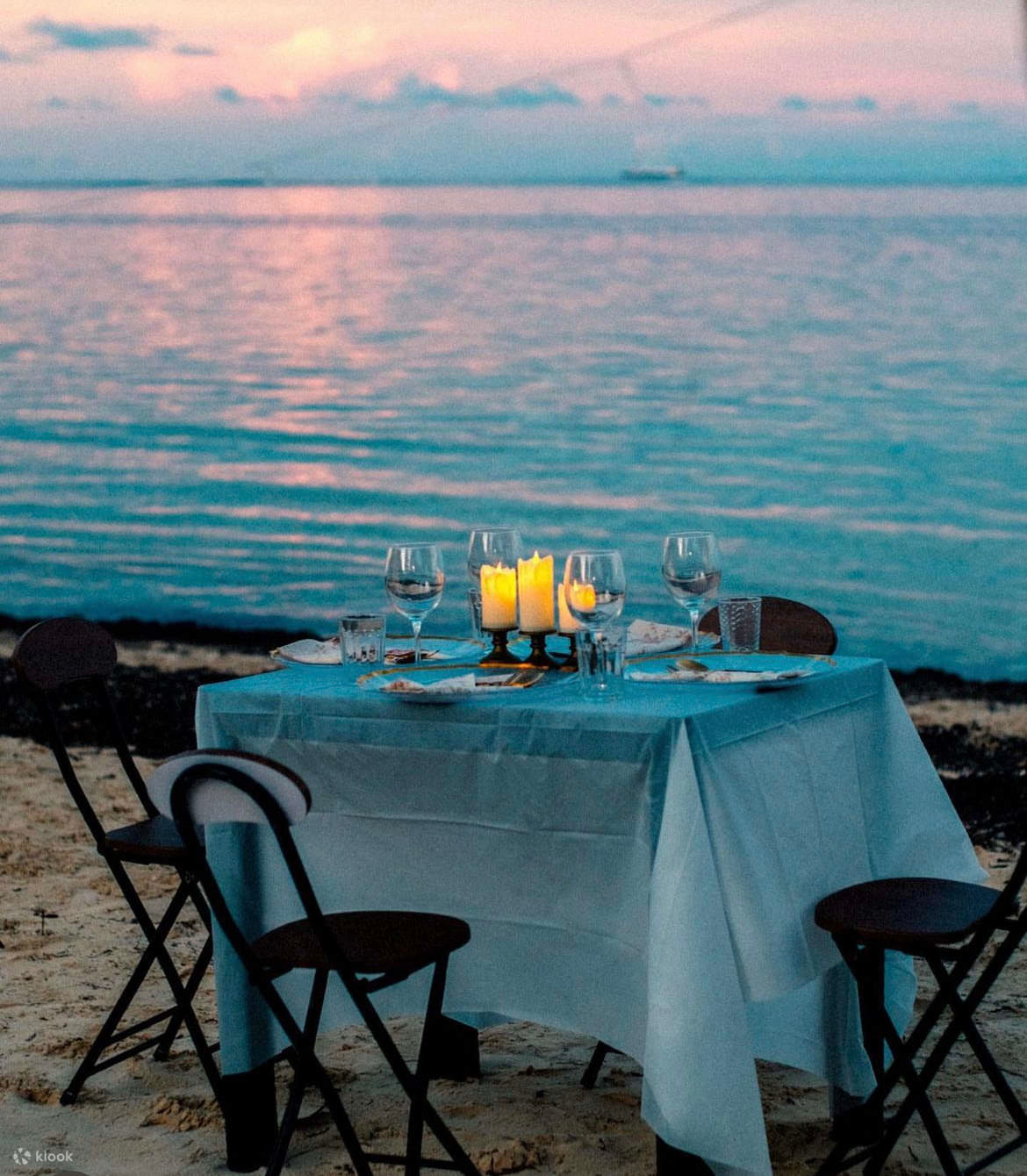 Romantic beachside dinner setup with candlelight at sunset for couples seeking a serene getaway