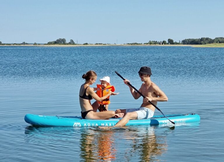 Family enjoying paddleboarding on calm waters in Saaremaa, Estonia, showcasing outdoor seaside adventure and relaxation