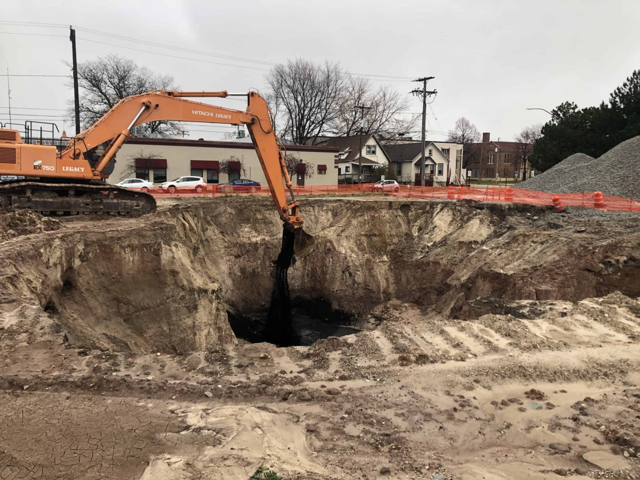 Excavator digging and removing contaminated soil during environmental remediation to control odours and pollution