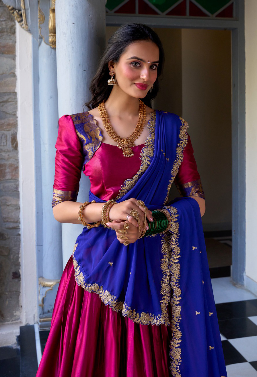 Traditional Bathukamma attire featuring a pink silk half saree with royal blue embroidered dupatta and gold jewelry typical of Telangana festive wear