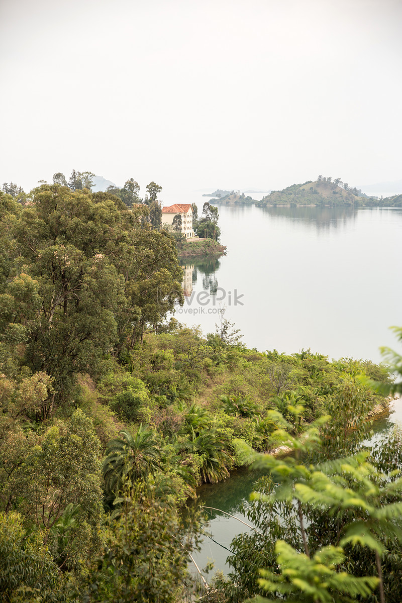 Scenic view of Lake Kivu in Rwanda with lush greenery and calm waters reflecting a lakeside building and nearby islands.