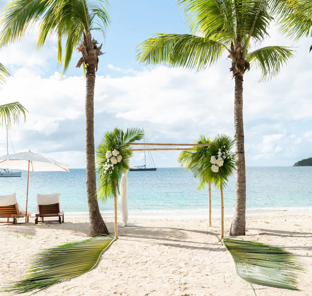 Wedding arch on a serene Antigua beach with white sand and turquoise waters at a luxury resort setting