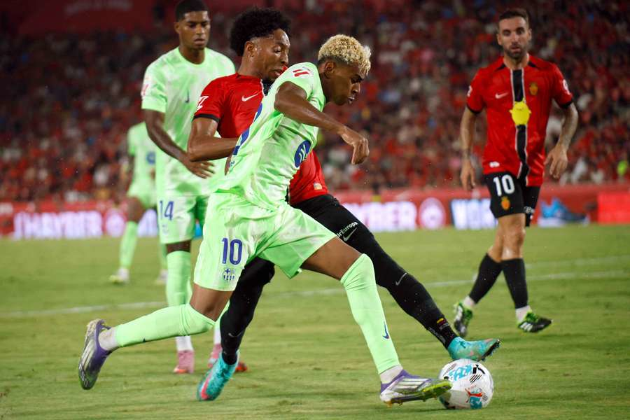 Two football players contest for the ball in an intense match moment, showcasing dribbling and defensive challenge
