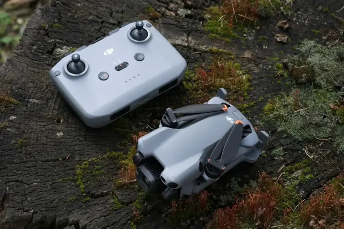 DJI Mini 5 Pro drone and its remote controller resting on a tree stump, showcasing the compact and portable design of the new drone model