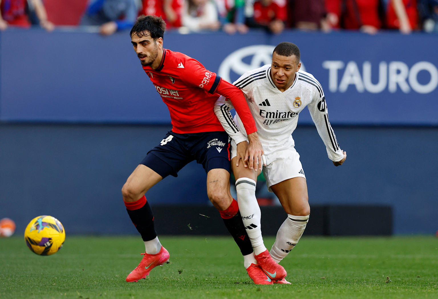 Players from Osasuna and Real Madrid compete intensely for the ball during a LaLiga match
