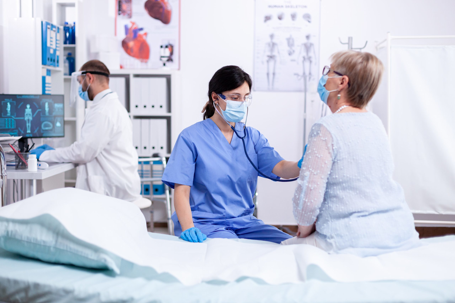 Cardiology consultation in a modern medical office with doctor examining patient near heart anatomy charts