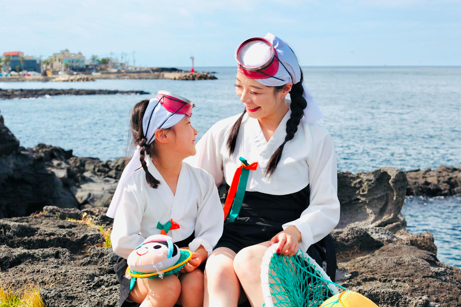 Haenyeo women in traditional harvesting attire on the rocky coast of Jeju Island, South Korea