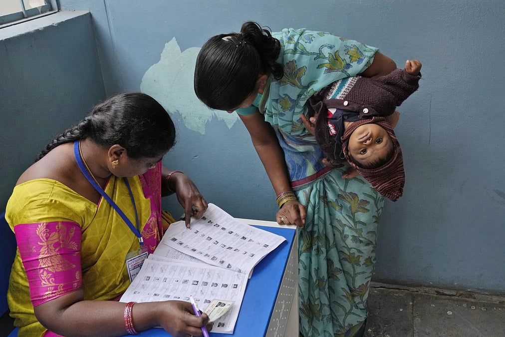 A voter with her child verifies her name in the electoral roll during the Telangana rural local body elections
