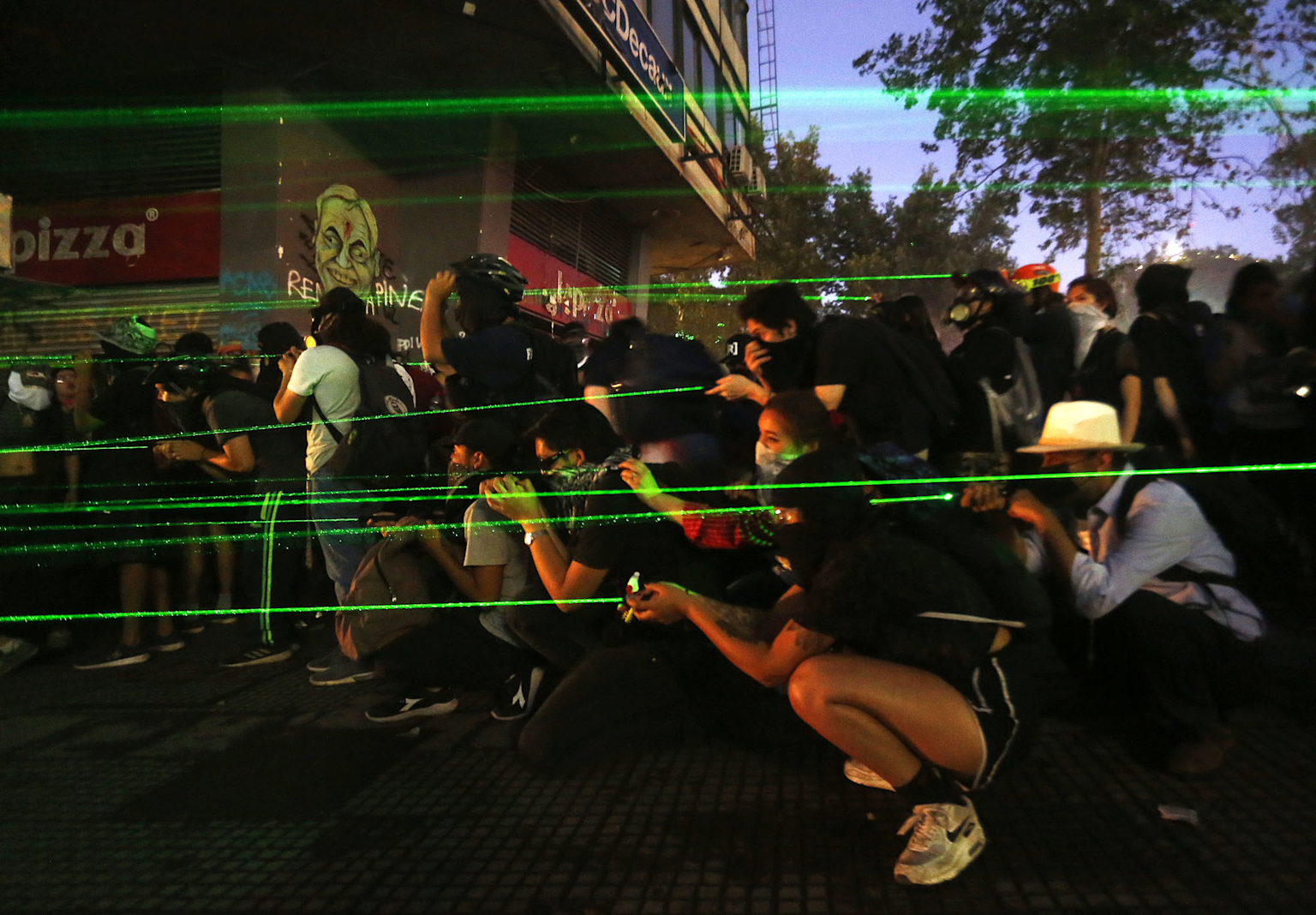 Protesters using green laser pointers to block surveillance cameras during a demonstration.