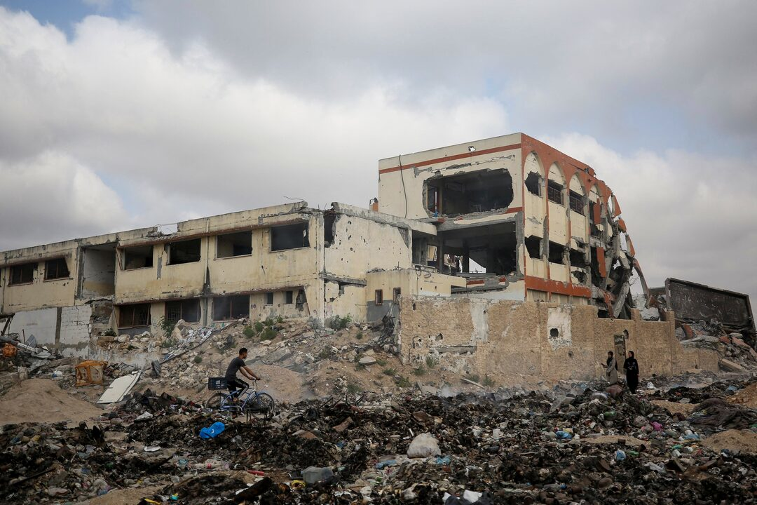 A heavily damaged school building in Gaza with rubble and debris in the foreground, illustrating the destruction of the education system